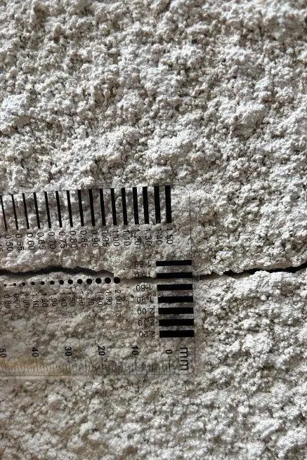 Réglette transparente graduée posée sur une fissure horizontale d'un enduit de façade