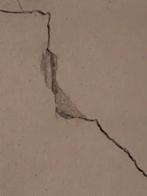 Gros plan d'une fissure en escalier sur un mur en béton de sous-sol